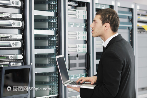 輕的IT工程師商務人員與薄的現(xiàn)代鋁筆記本電腦 網(wǎng)絡服務器機房中的高效協(xié)作